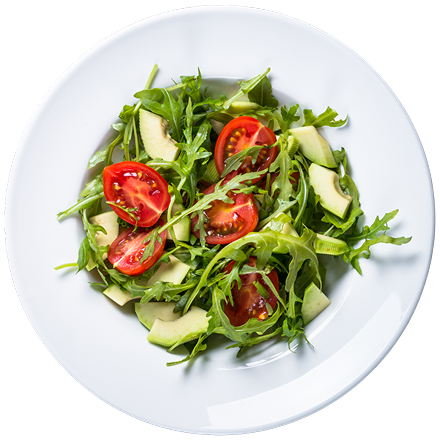 A white plate holds a fresh green salad with arugula, sliced avocado, and halved cherry tomatoes, viewed from above