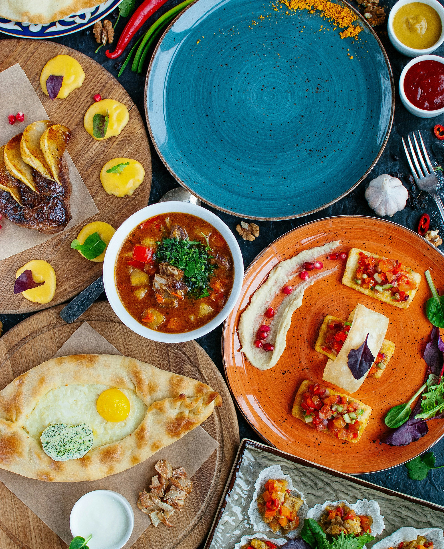 An overhead view of a table laden with various colorful dishes, including a stew, flatbread with an egg, and appetizer plates, hinting at a modern Moroccan or Middle Eastern meal